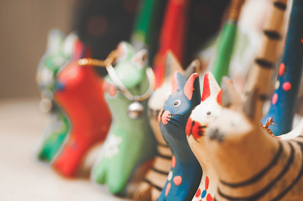 A charming display of colorful wooden cat figurines with soft focus effect.